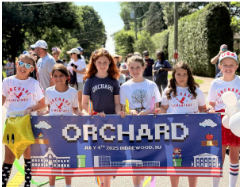 Orchard Students holding a banner that says orchard while marching in a parade