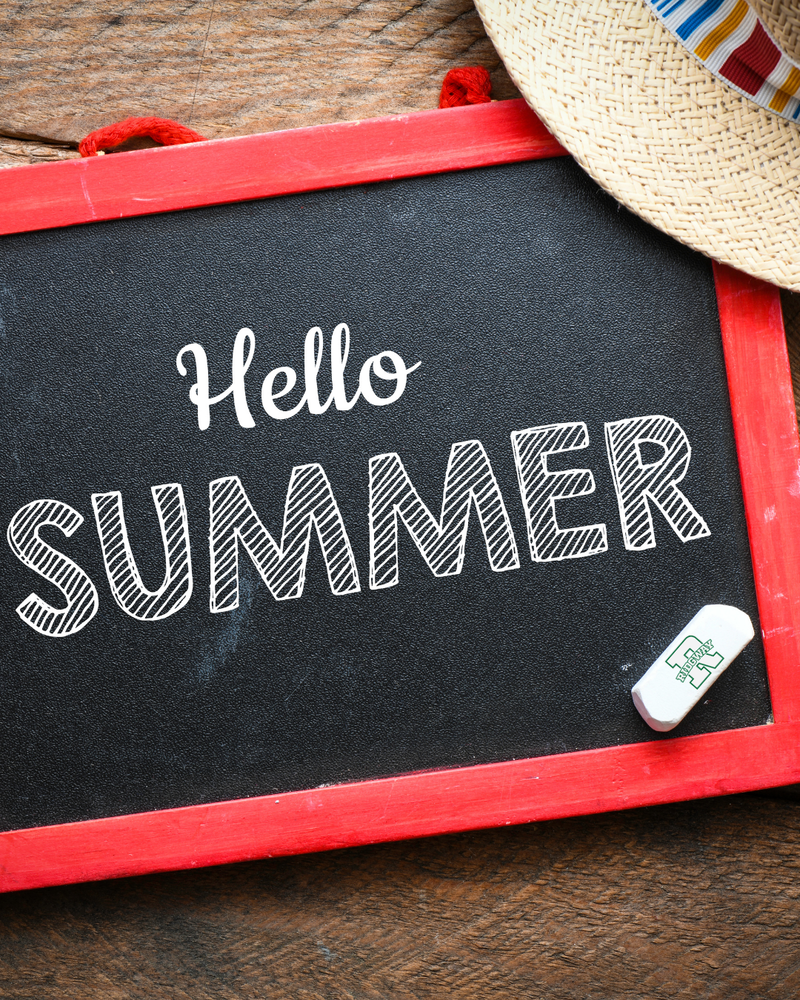 Chalkboard with the words 'Hello Summer' written in white lettering, next to a straw hat and eraser.