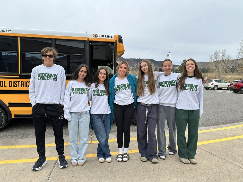 Outside group photo of the cross country team in front of yellow bus.