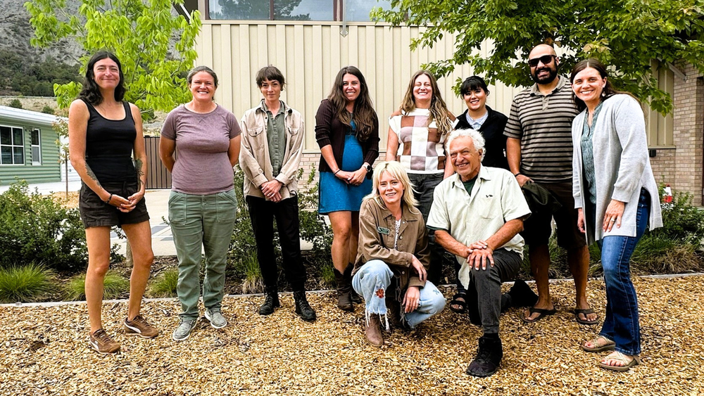 Ten staff members pose together outdoors in front of a building.