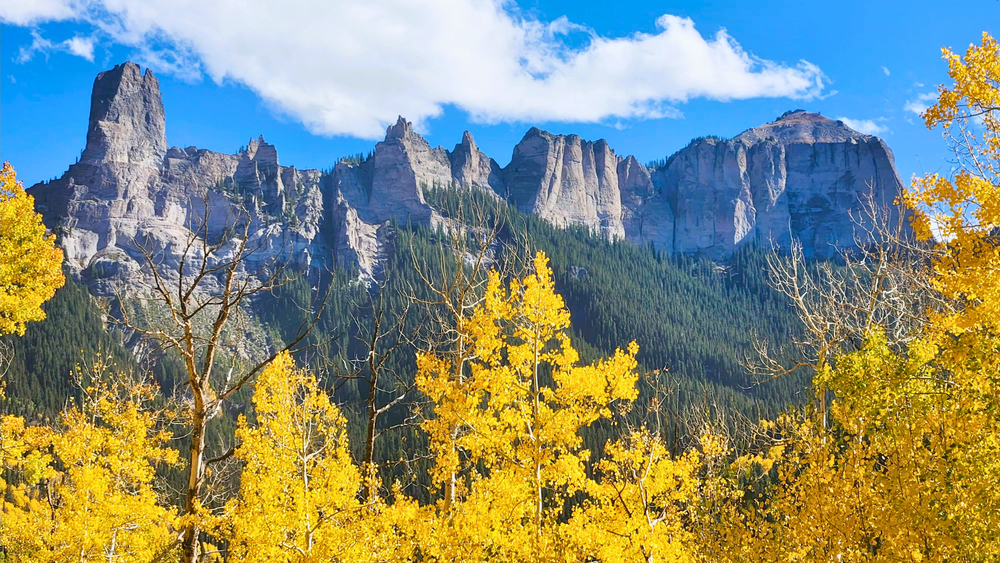 peaks framed by golden fall aspens under a bright blue sky.