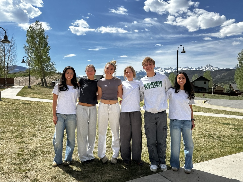 Six track and Field athletes standing together outside on a sunny day