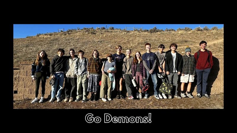 High school team posing outdoors together; text reads ‘Go Demons!’