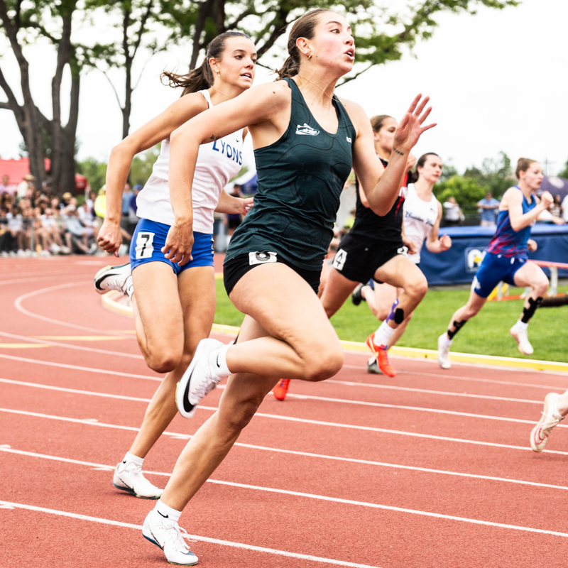 Female track athletes running on track during the Colorado State Track & Field Championships on a sunny day.