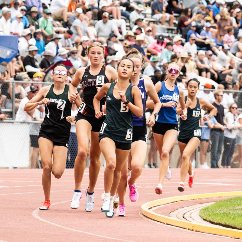 Female track athletes running on track during the Colorado State Track & Field Championships on a sunny day.
