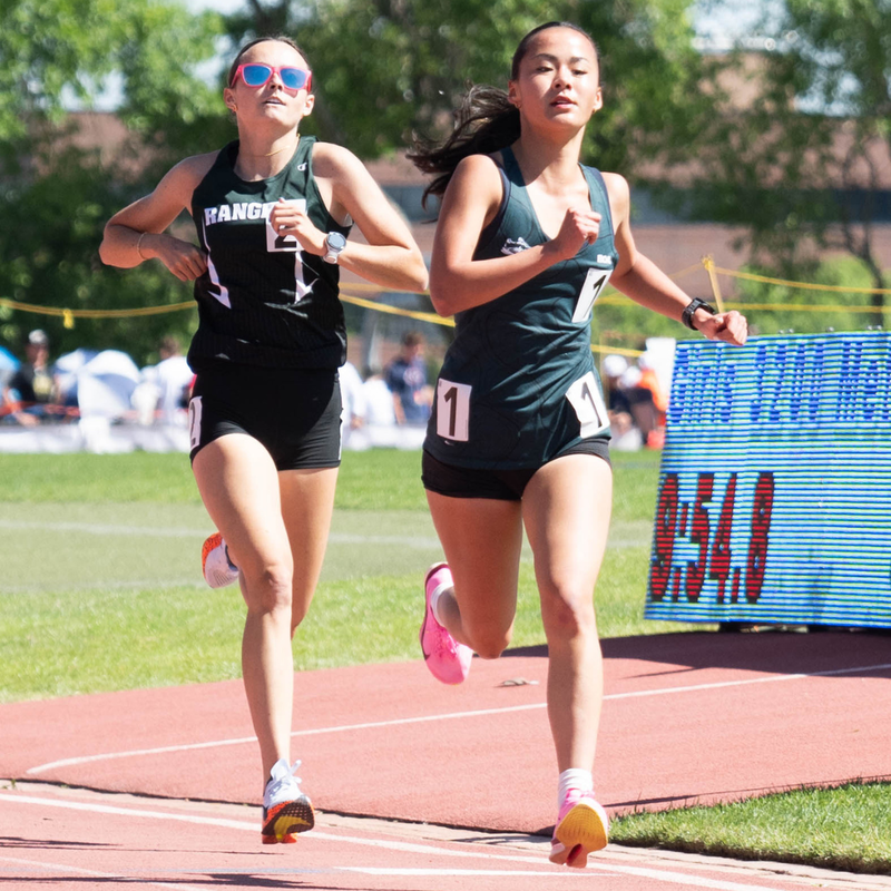 Female track athletes running on track during the Colorado State Track & Field Championships on a sunny day.