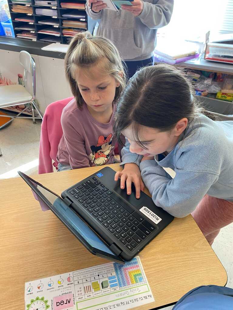 Two young ladies working together on a laptop.