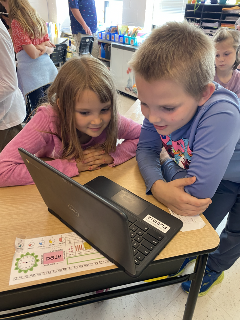 A girl and a boy reading on the laptop.