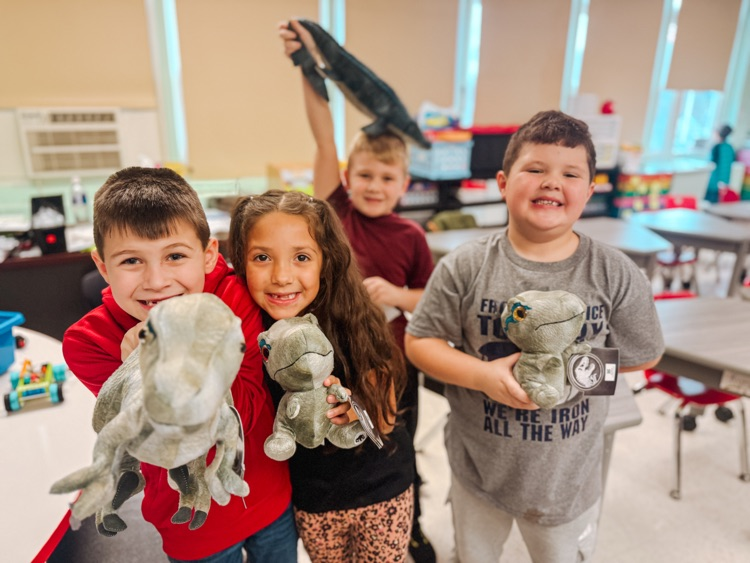 first grade students holding their dinosaurs from the Dino-mite attendance surprise