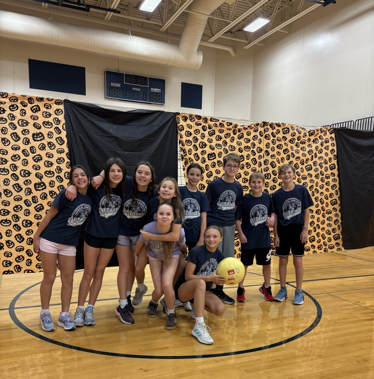 pe class posing in front of volleyball net