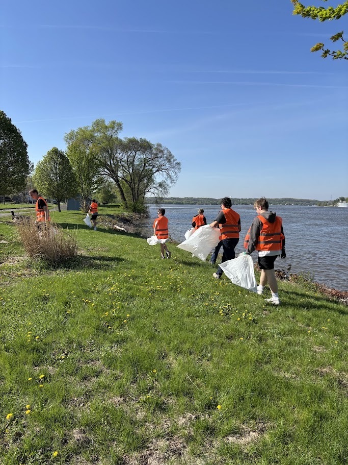 students in high-viz vests cleaning near the river