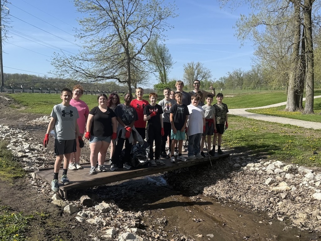 students standing on a bridge over a creek