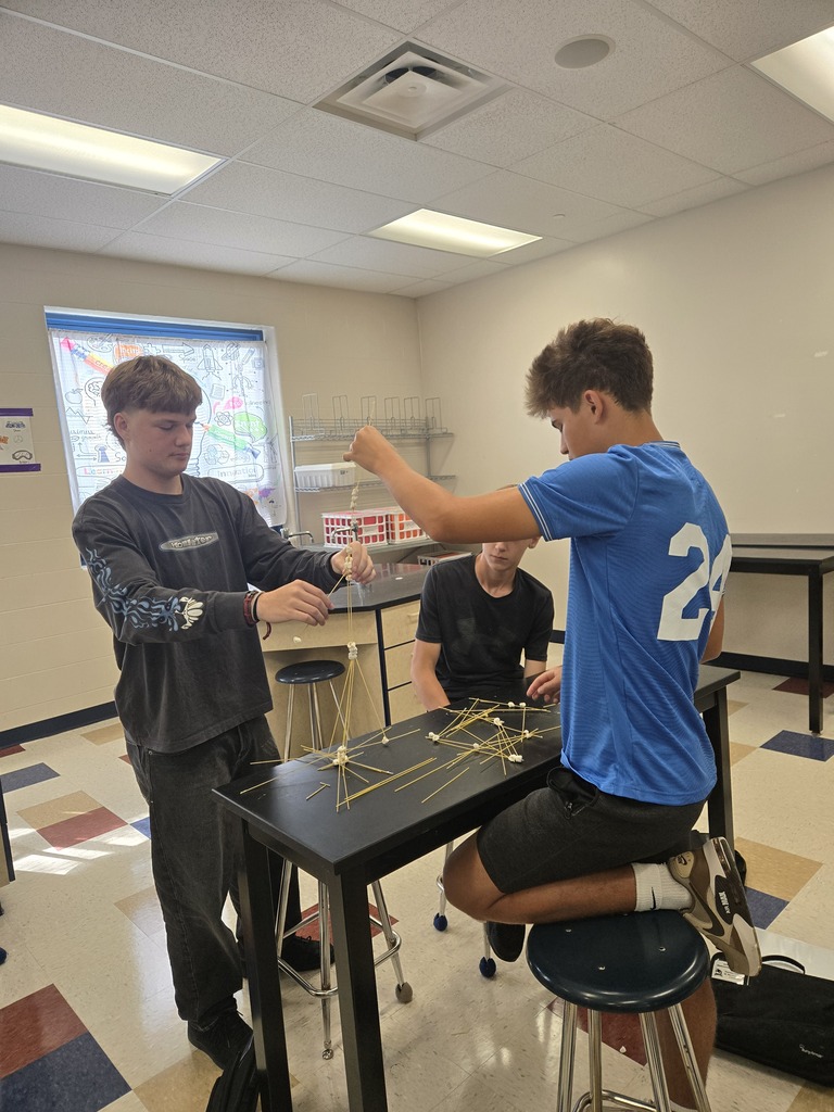 three students building tower only using marshmallows and spaghetti noodles