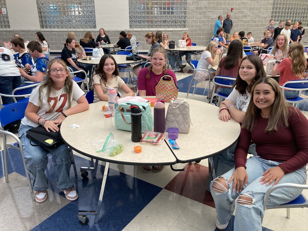 Image includes students during their lunch period smiling bit for the First day of school