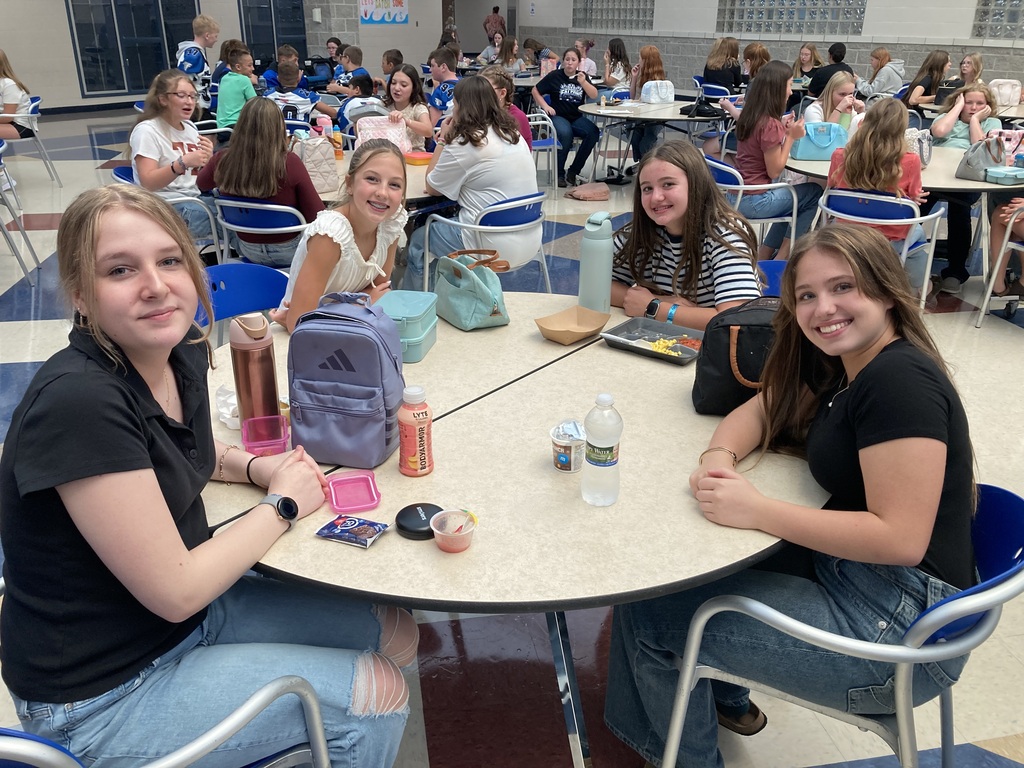 Image includes students during their lunch period smiling bit for the First day of school