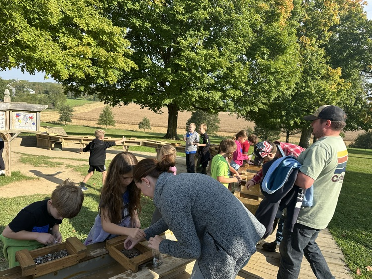adults assisting students with gem mining activity