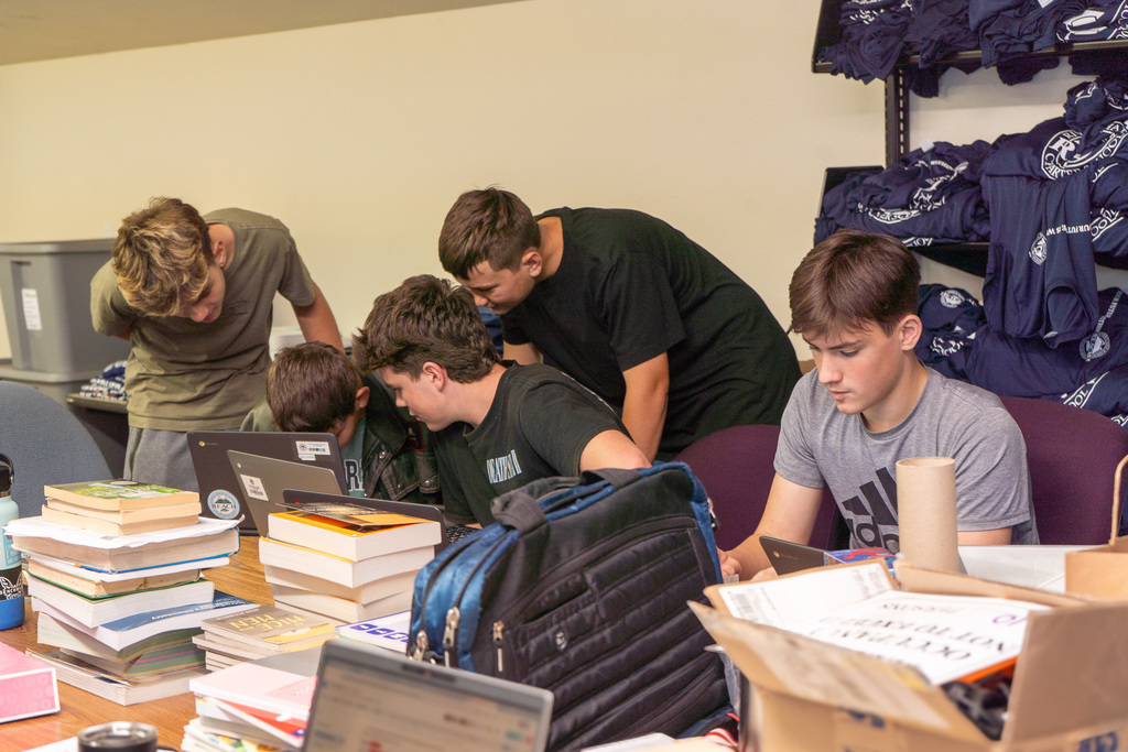 Several students gather around a laptop while studying