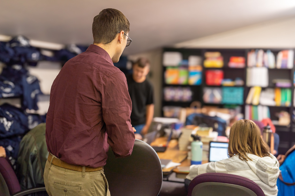 A male teacher helps students study in a library