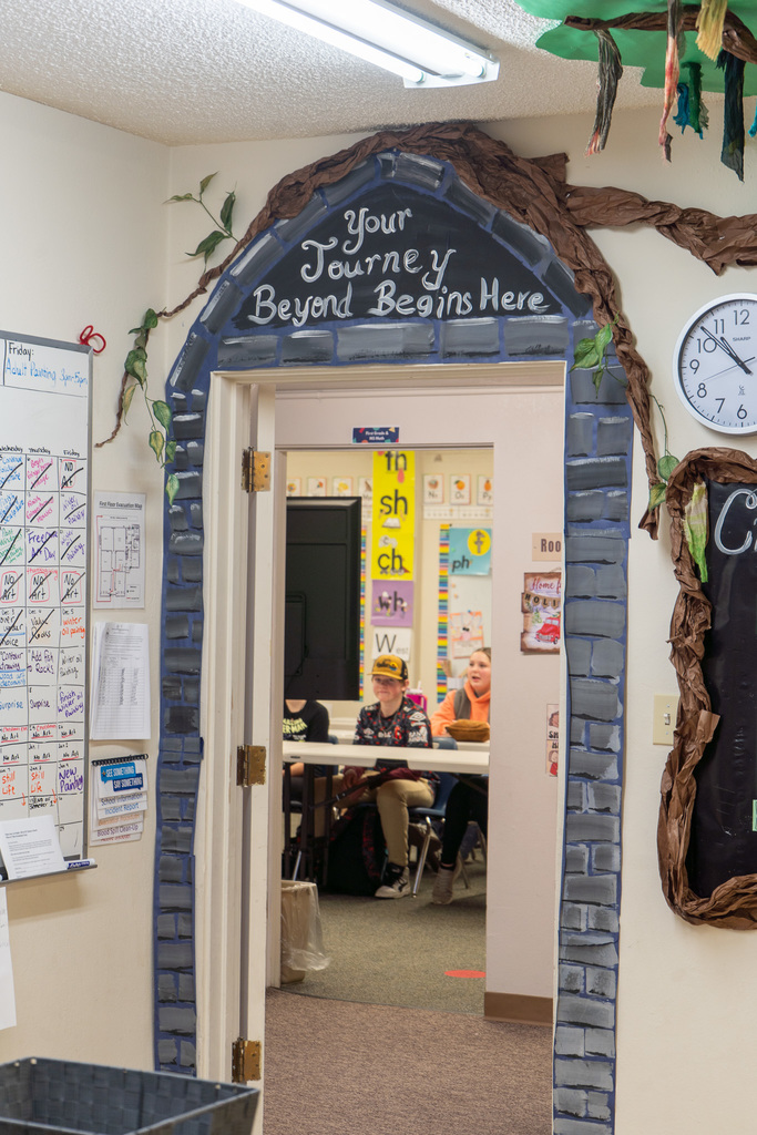 The words "Your Journey Beyond Begins Here" are painted over a doorway, through which you can see students sitting at desks. 