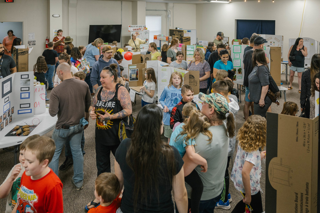 Many people navigate display boards assembled by students.