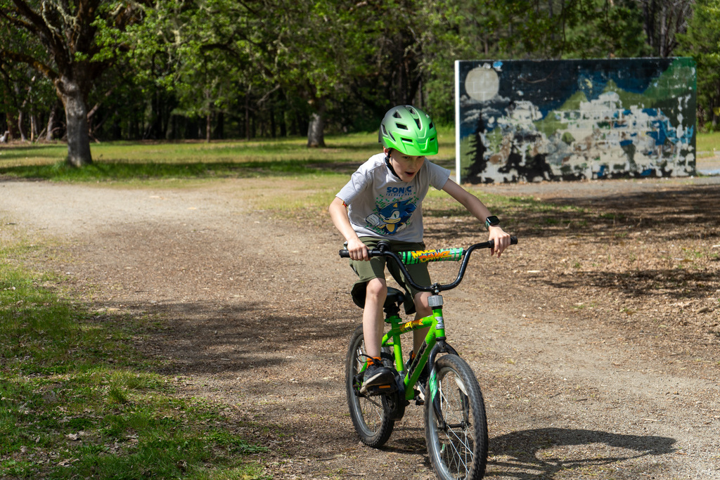 A boy is standing up on his bike pedals as he rides.