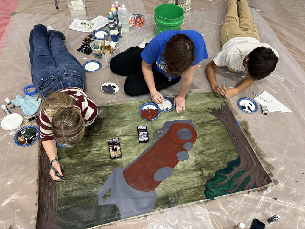 students painting details on the mural