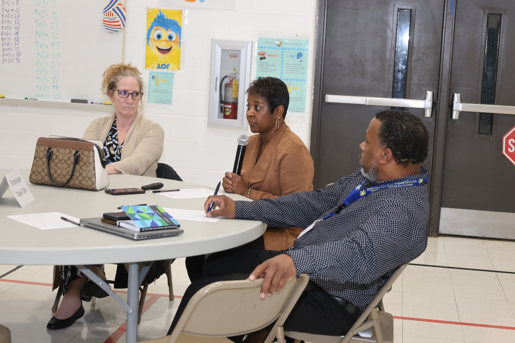 Three people having a discussion while seated at a table