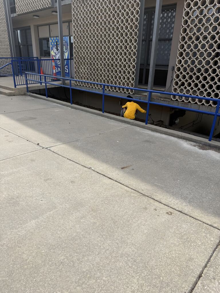 student picking up trash near building