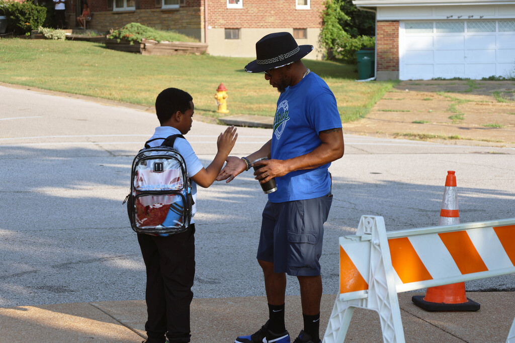 student giving high five to staff member, outside