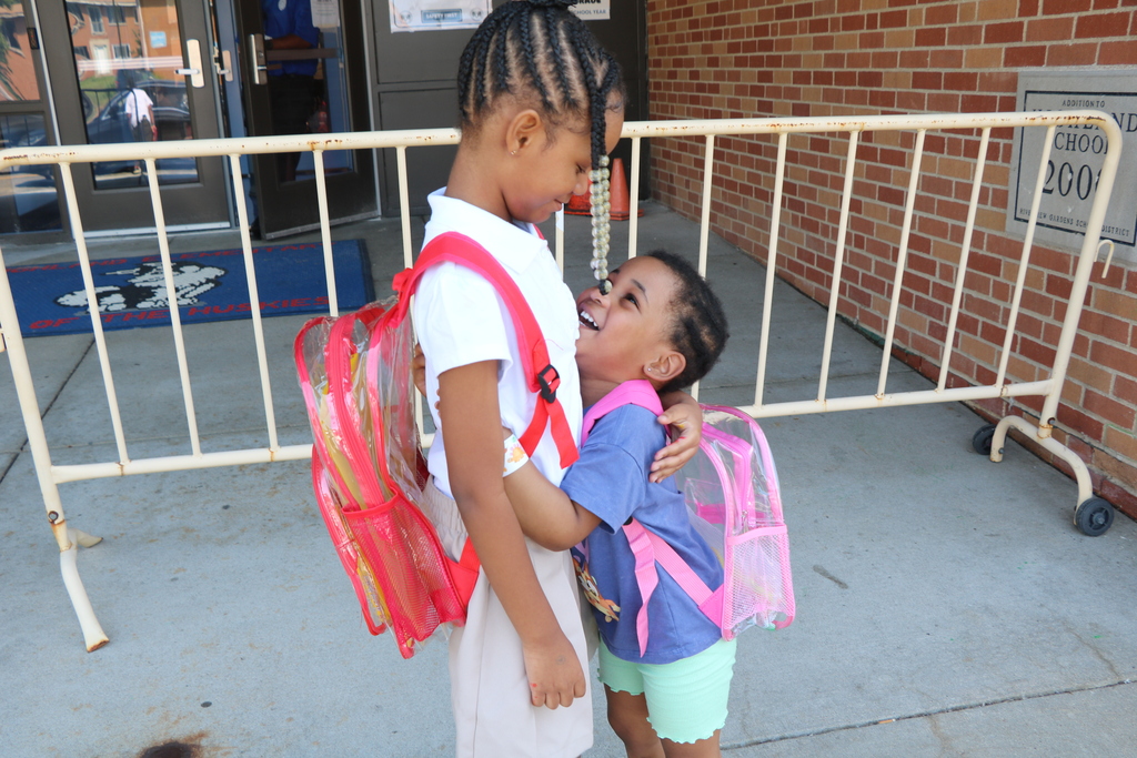 two students hugging and smiling outside school