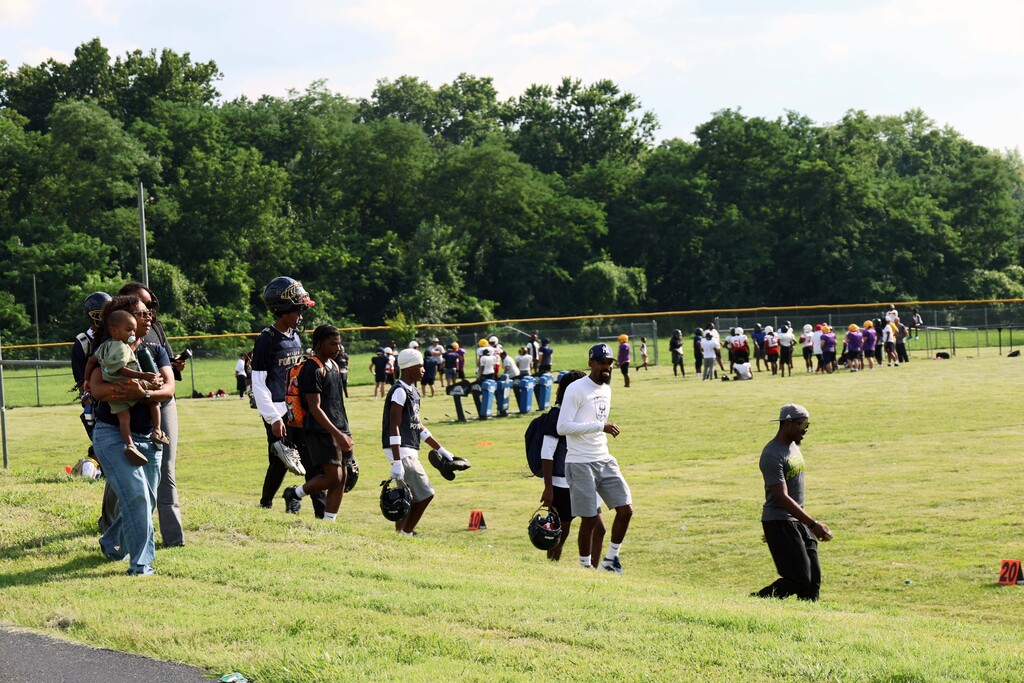 Football players, coaches and family members walk to the football field
