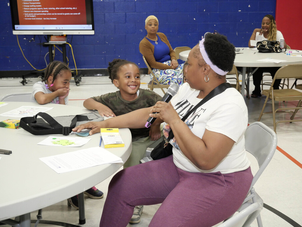 Woman talking into microphone while child looks on