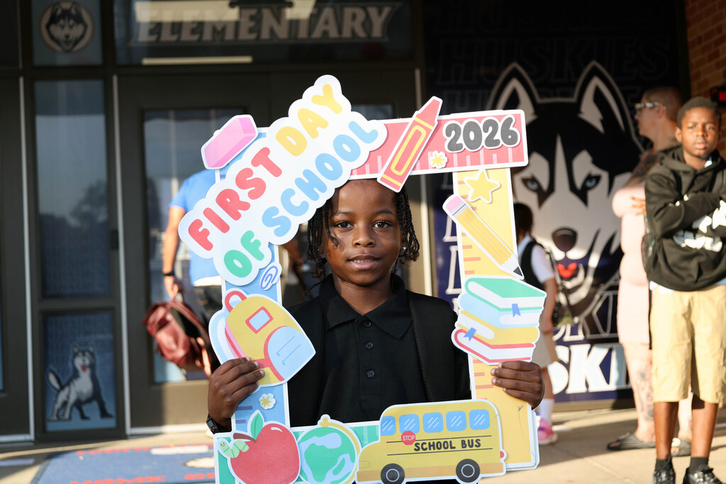 Highland student standing with First Day of School sign