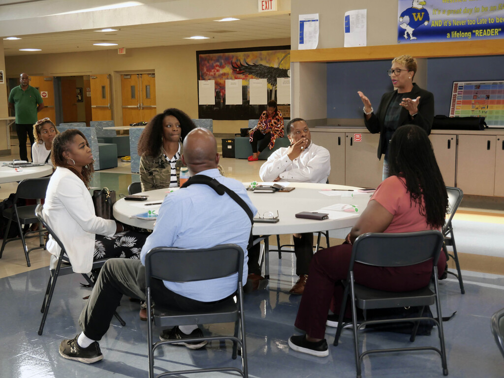 People at round table listening to a woman speak