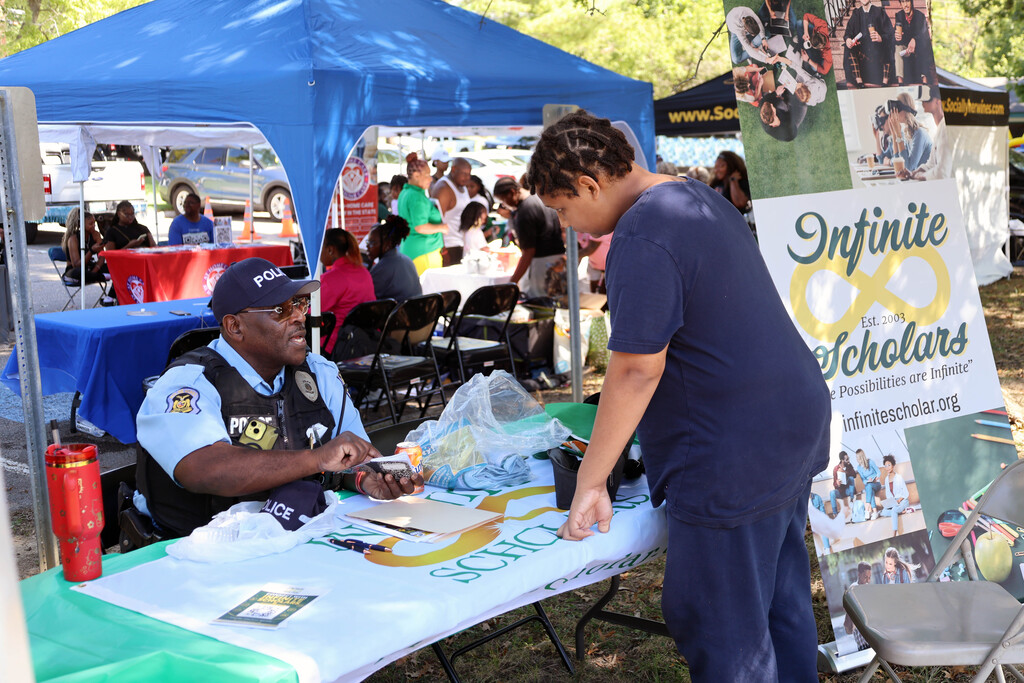 A male student talks to an offer at the Infinite Scholars table