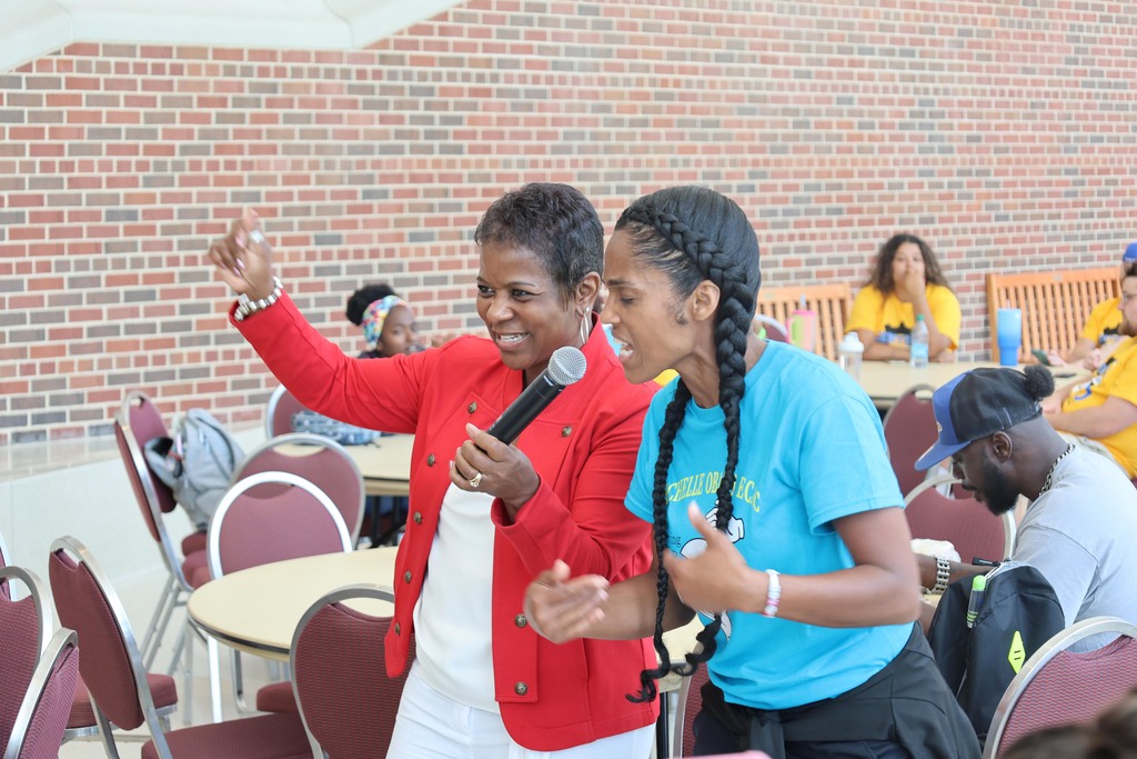 Dr. Tanya Patton holds mic while woman sings
