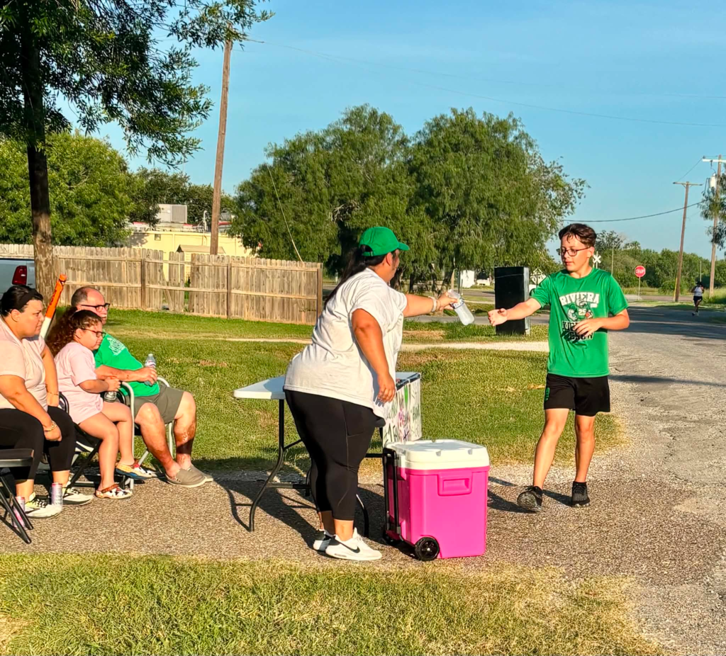 Mrs. DeLaRosa handing out a water to a CC runner. 