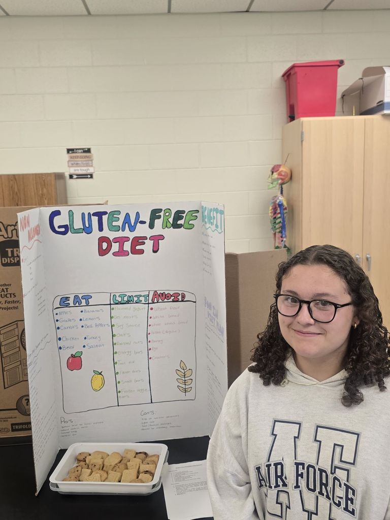 student posing with the poster and food they prepared