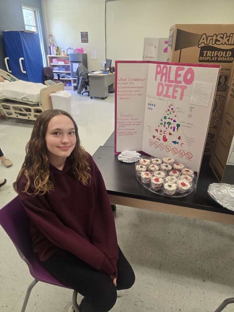 student posing with the poster and food they prepared