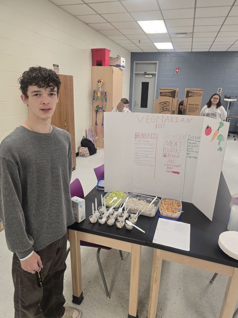 student posing with the poster and food they prepared
