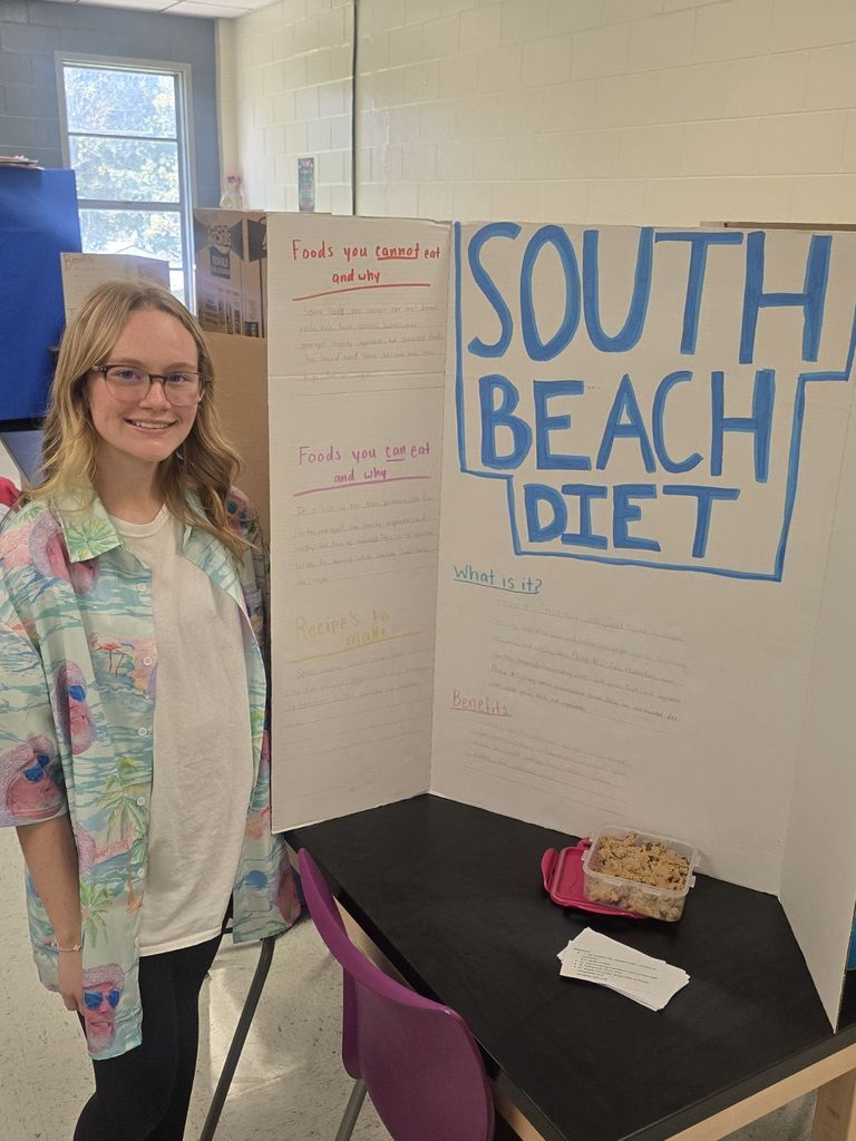 student posing with the poster and food they prepared