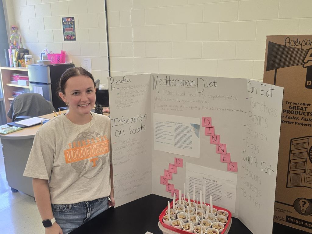 student posing with the poster and food they prepared
