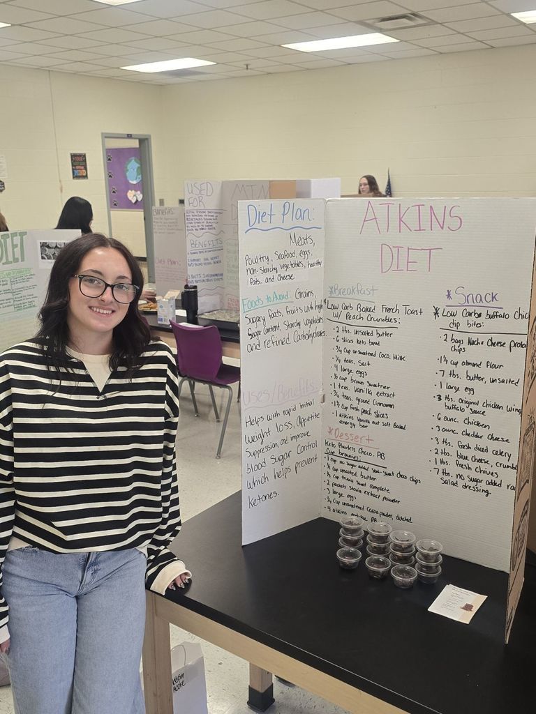 student posing with the poster and food they prepared