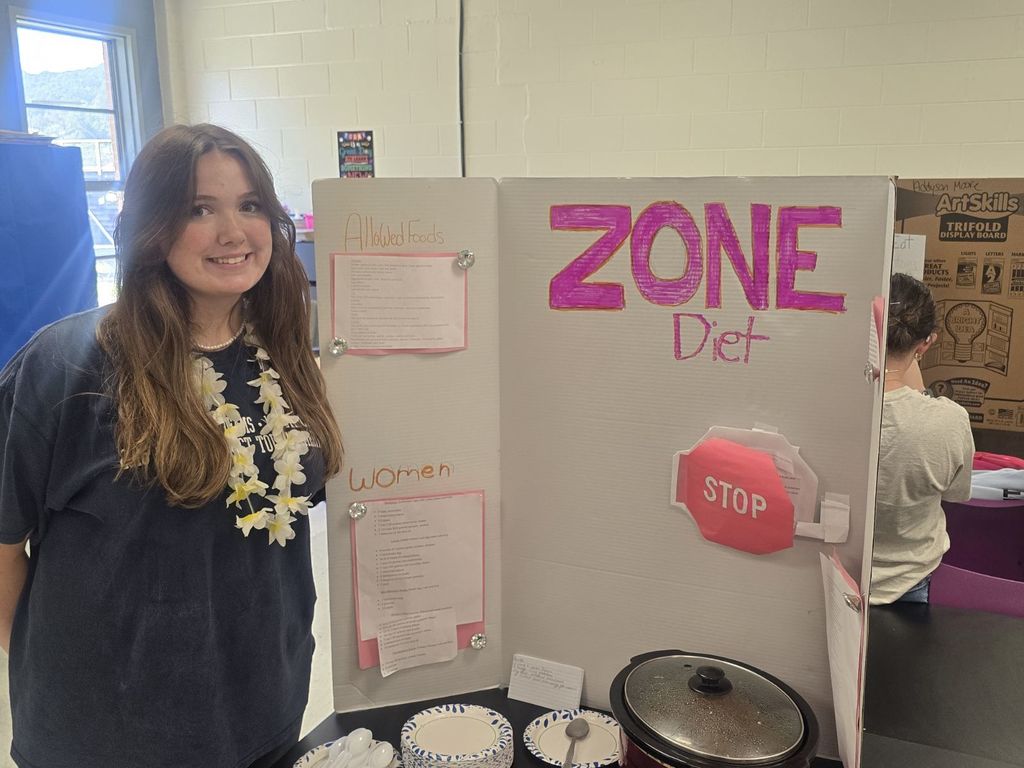 student posing with the poster and food they prepared