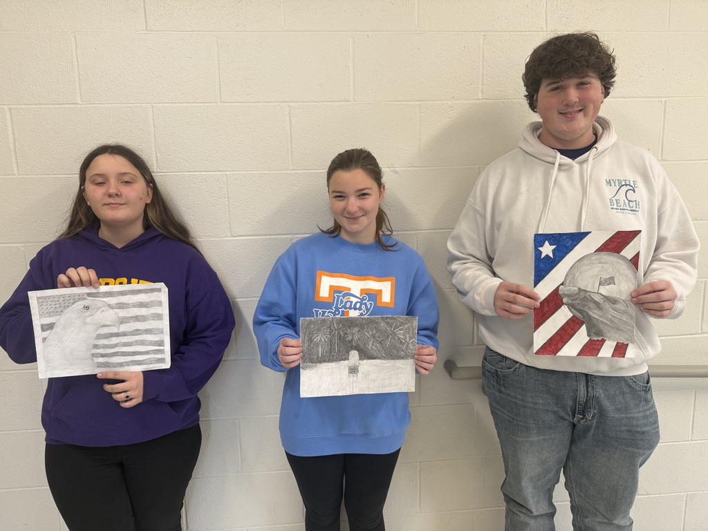 art students holding their winning submissions