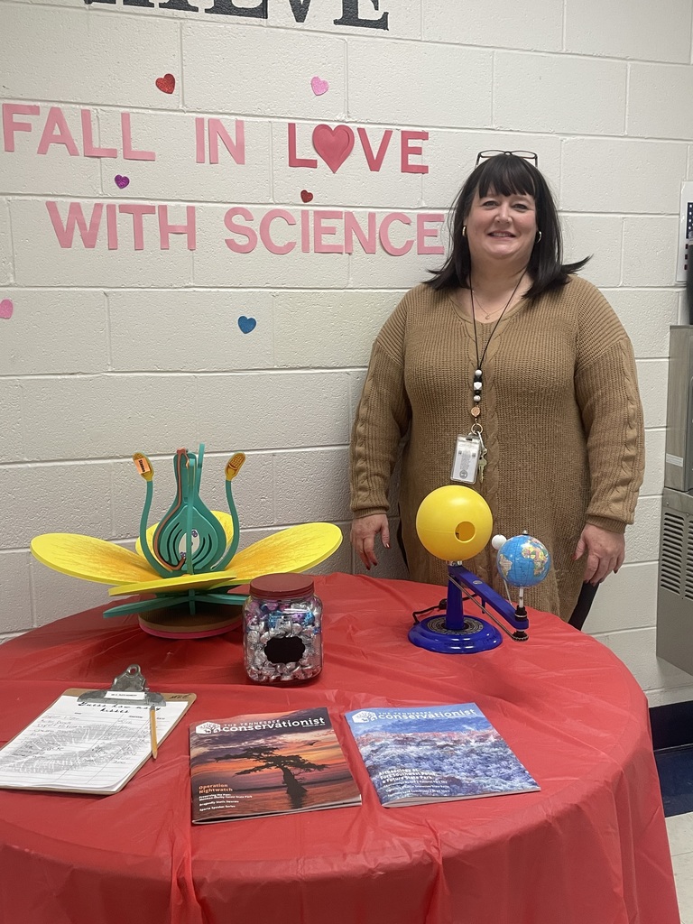 Mrs. Ann next to achieve table containing science models with "Fall in Love with Science" on the wall