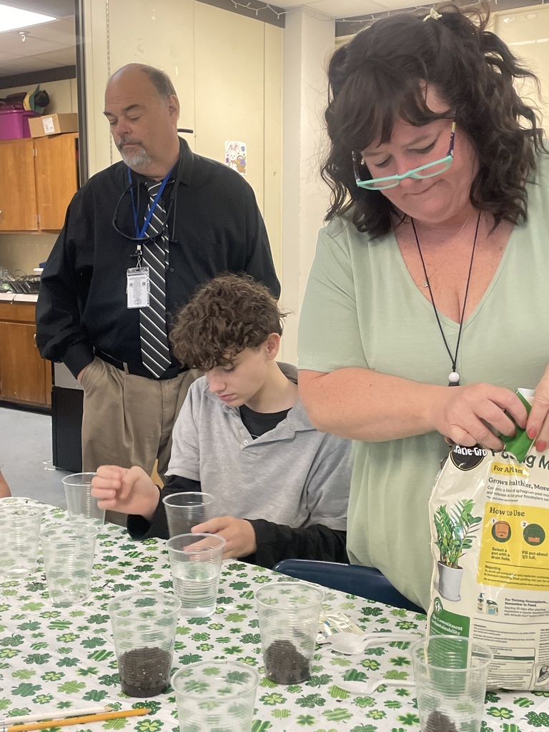 Mrs. Ann and Mr. Johnson helping student plant tomato seeds.