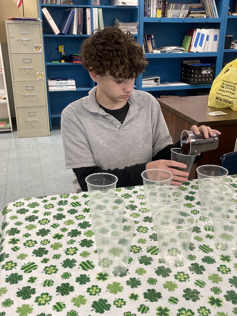 Student adding dirt to cups for planting.