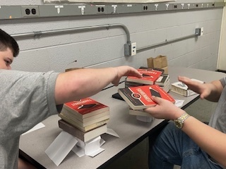 Students balancing books on index card structure