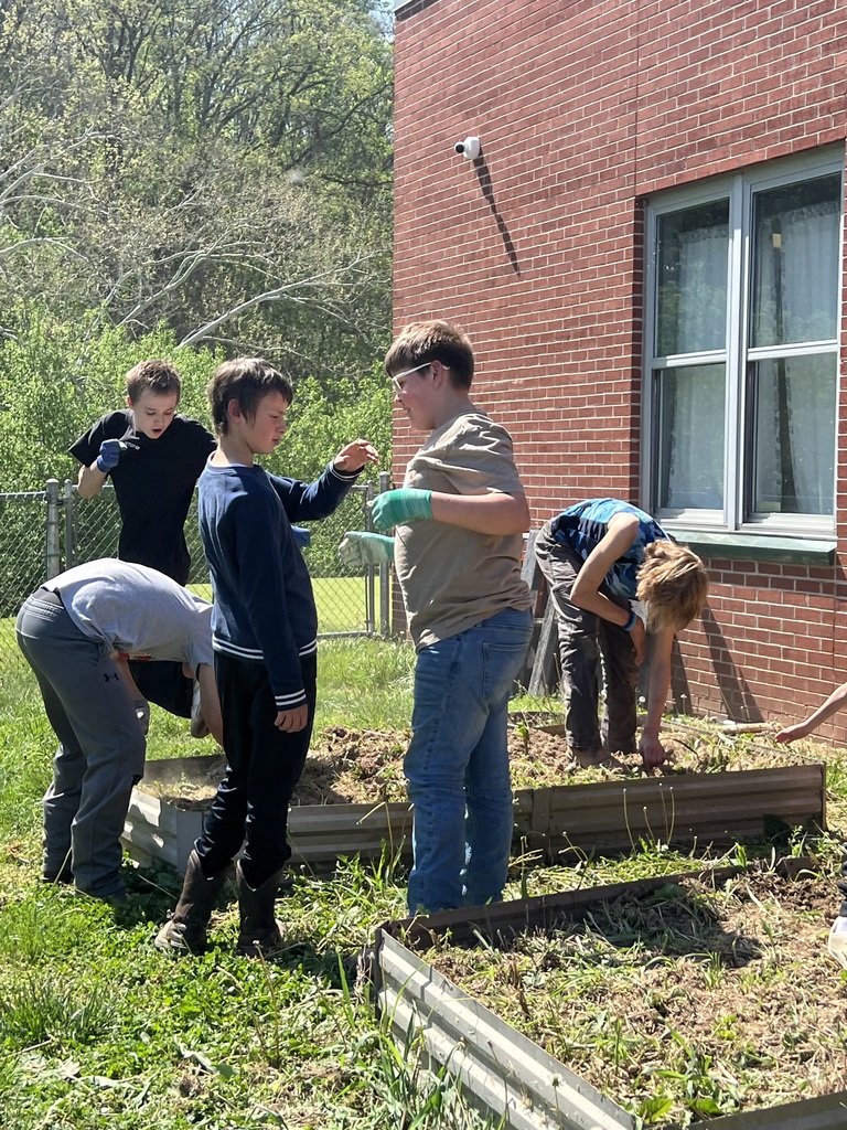students talking to each other with gloves and others planting seeds in the garden